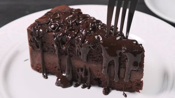 Eating piece of chocolate cake with fork.