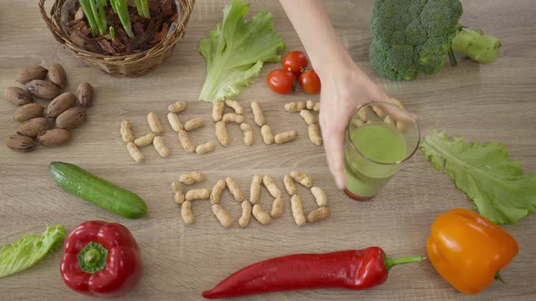 Almond Nuts in Healthy Food Shape with Vegetables and Female Hand Putting Glass of Healthful Green