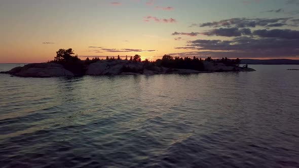 Flying over Waves to Island in Blue Lake at Sunset, Drone Aerial Wide Dolly In. Pine Trees, Colorful