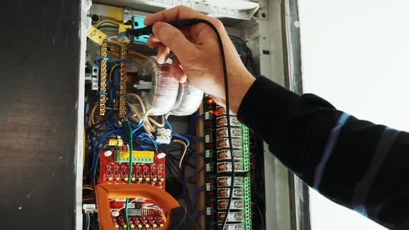 Electricians hands testing current  electric in control panel.