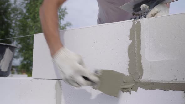 builder applies adhesive composition or solution with spatula to wall structure.