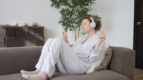 Young Woman Using Smartphone Relaxing On Couch In Living Room