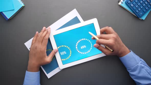 Man's Hand Working on Digital Tablet at Office Desk Using Self Created Chart