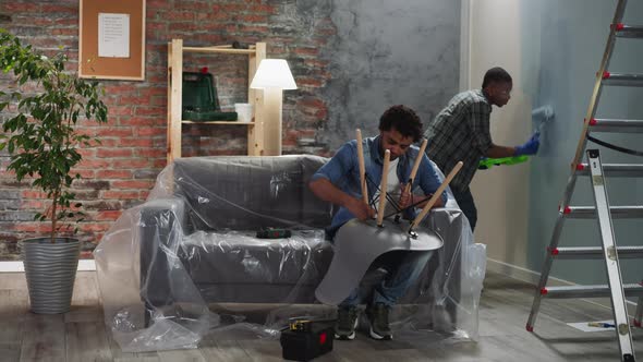 AfricanAmerican Guy Paints Wall Brother Assembles Chair