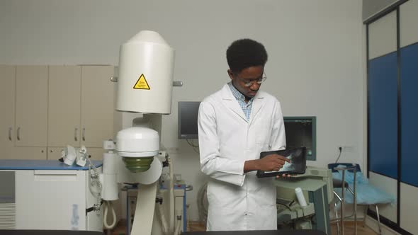 Young African American Man Doctor in White Uniform and Eyeglasses Demonstrating