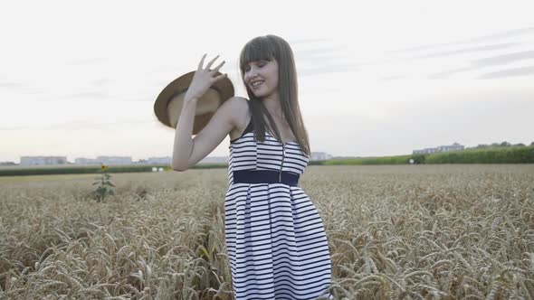 Happy, Playful Girl Poses with Hat in Wheat Field