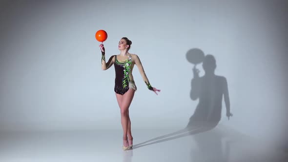 Gymnast Professional Spinning a Ball on One Finger. White Background. Slow Motion