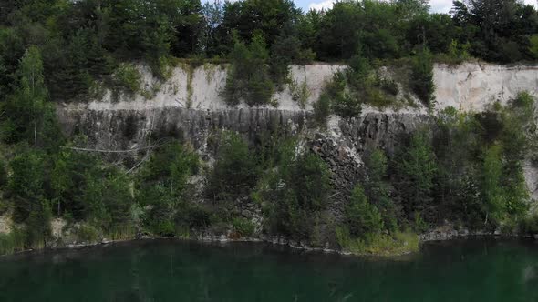 Aerial View of a Quarry Tracking Backward Revealing Lake with Still Water