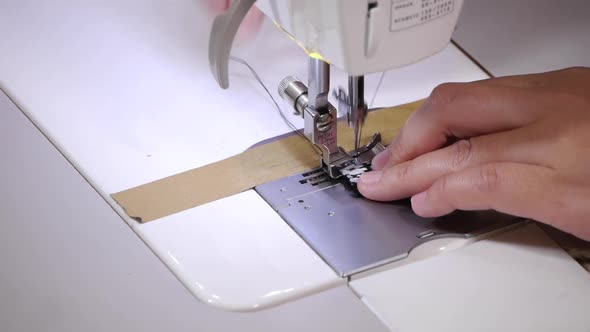 Extreme close up on finger pushing strip of thick fabric with triangle shaped patterns through sewin