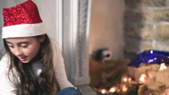 Young Little Girl Prepares Christmas Nativity Scene at Home Wearing a Christmas Red Hat
