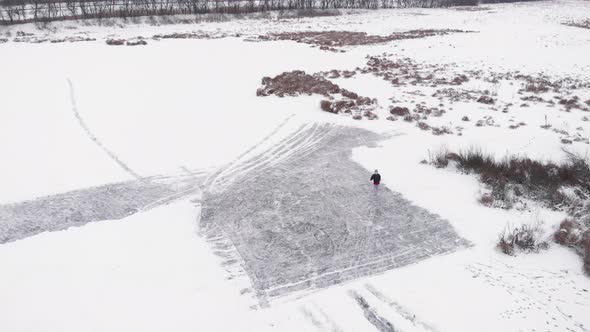 Woman in figure skates is skating on frozen lake ice