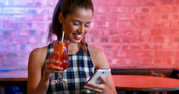 Happy woman taking selfie on mobile phone while having cocktail