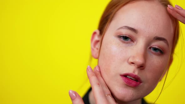 Closeup Face of Freckled Redhead Slim Caucasian Woman on the Right Touching Cheek with Hand Looking