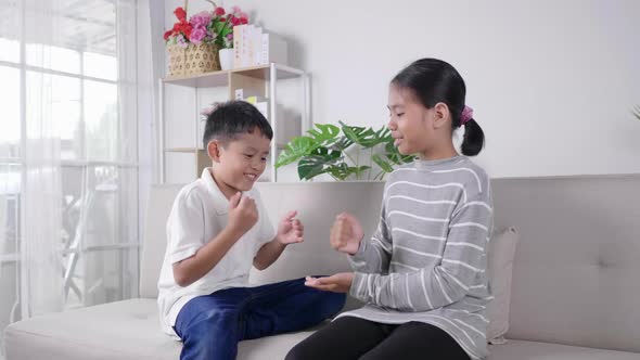 2 kids sitting and playing rock paper scissors game together with happy and laughing