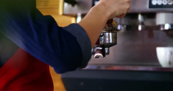 Waitress using a tamper to press ground coffee into a portafilter