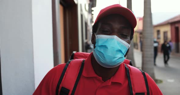 African man with thermal backpack working for food delivery while wearing safety face mask