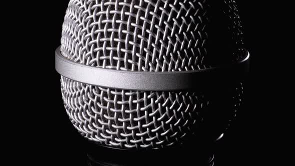 The Microphone Rotates on a Black Background. Dynamic Microphone Grid Spins Close-up