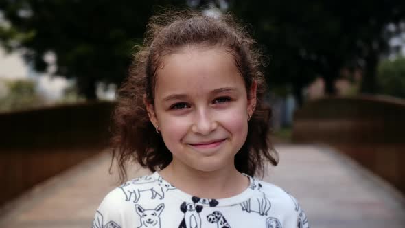 Portrait Little Happy Child Girl Looking at Camera Standing on Street in City on Summer Day