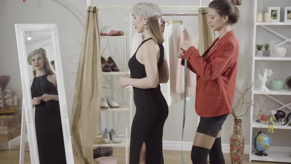 Side View of Elegant Lady Standing in Atelier in Front of Mirror As Seamstress with Measuring Tape