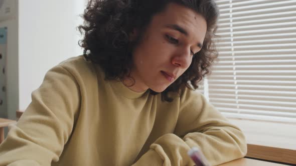 Guy Writing in Notebook on Lesson