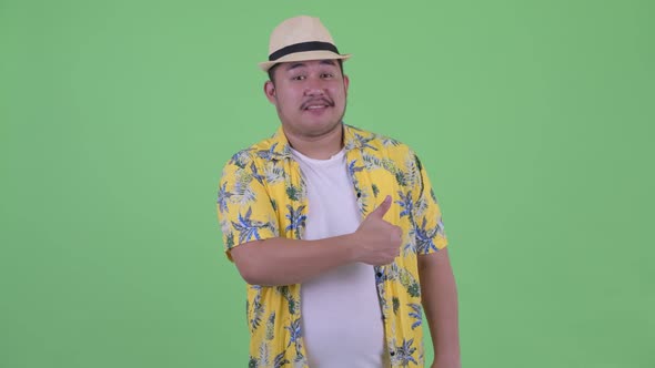 Happy Young Overweight Asian Tourist Man Giving Thumbs Up