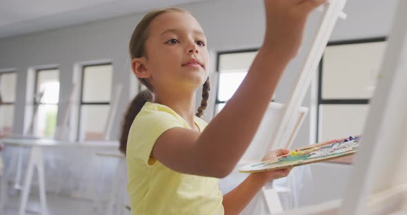Video of focused caucasian girl painting during art lessons at school