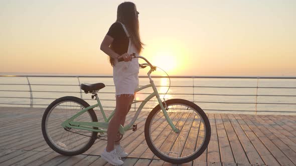 Young Attractive Woman with Long Hair is Having a Good Time on Sea at Sunset or Sunrise