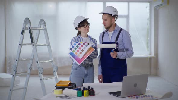 Female Designer with Color Palette and Professional Male Builder with Roller for Painting Walls in