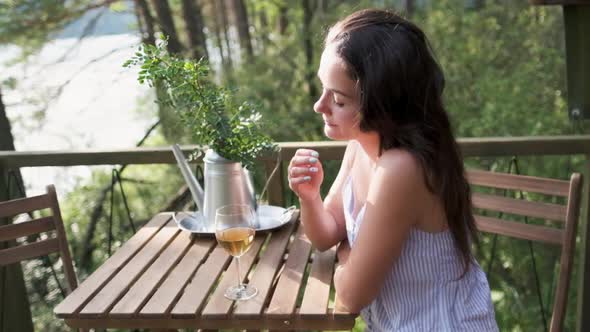 Attractive Brunette with a Glass in Her Hands Enjoying Nature in the Mountains, Sitting on the