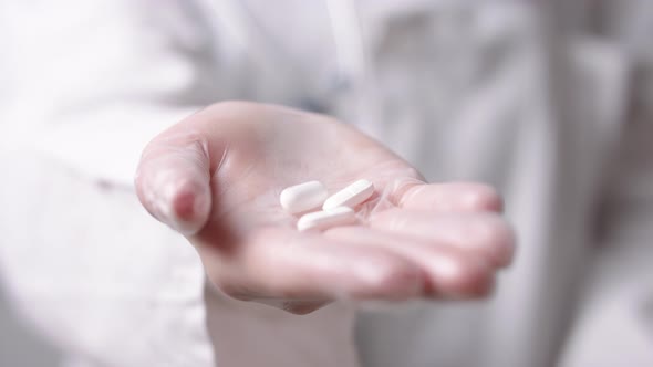 Close Up, Doctor Holding White Pills in Hand with the Glove. Medication and Cure for the Flu