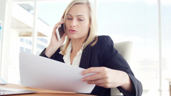 Businesswoman talking on the mobile phone at her desk