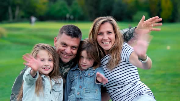 Portrait of Happy Family Waving Hands at Park.