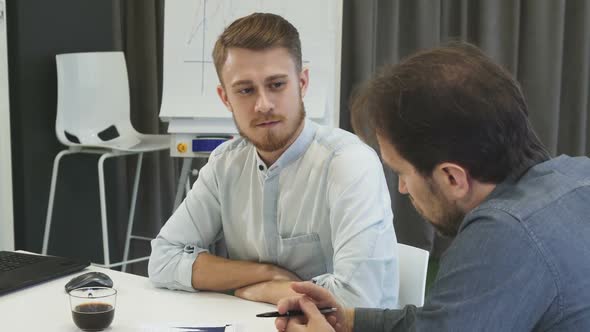 Young Businessman Listening To His Mature Colleague During the Meeting