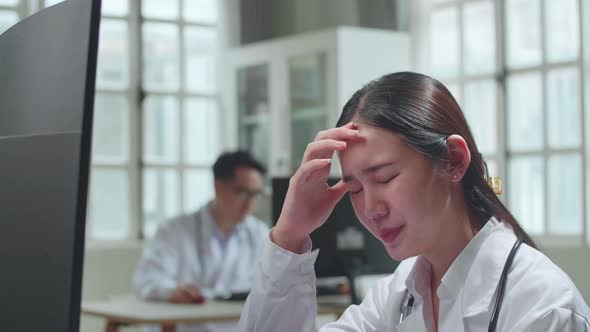 Young Asian Woman Doctor Is Using Computer And Headache In Workplace. Medical Concept