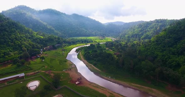 Slow backwards aerial shot revealing a beautiful river cutting through the jungles of an elephant pa