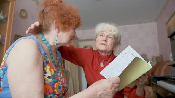 Happy Senior Woman Hugs Friend Holding Notebook Near Piano