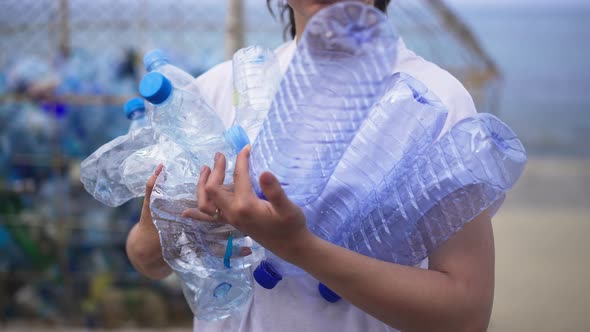 Unrecognizable Slim Young Woman Holding Empty Used Plastic Bottles Turning Walking to Garbage