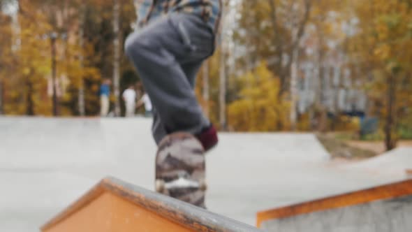 Skater Practicing in the Autumn Concrete Skate Park Making Tricks and Rides in Ramp