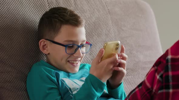 Closeup of a Caucasian Child Laying on a Couch Enjoying Playing Online