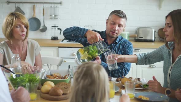 Man Pouring Lemonade and Juice in Drink at Family Gathering Dinner