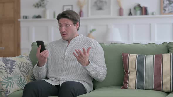 Man having Loss on Smartphone at Home