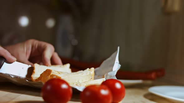 Closeup of Hand Cutting French Cheese Marquis Castello