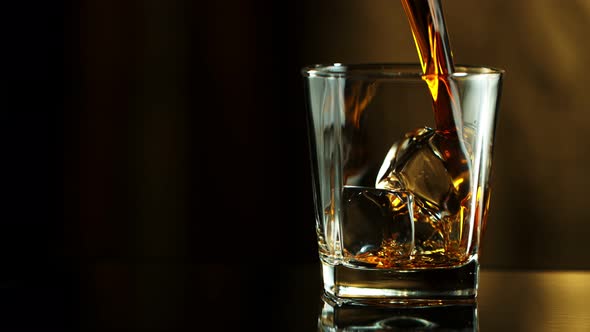 Super Slow Motion Macro Shot of Pouring Whiskey Into Glass with Ice Cubes at 1000Fps