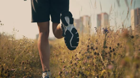 Trail Runner On Field Workout.Man Athlete Legs Jogging On Field.Runner Cardio Exercising Outdoor.