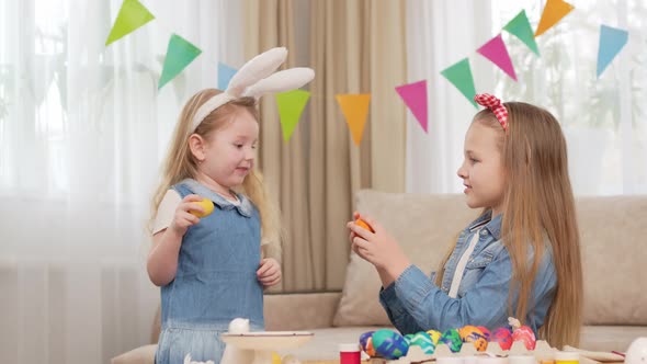 Little Girls with Rabbit Ears Play with Easter Eggs in Game of Who Will Break