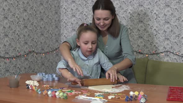 A little girl with her mother are preparing gingerbread