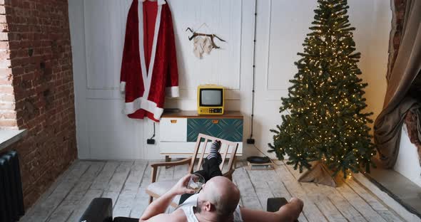 Man Sitting on Sofa at Home Waiting for Christmas Preparing to Work As Santa