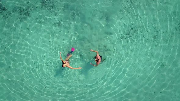 Aerial view of man and woman with masks and flippers swimming on their backs.