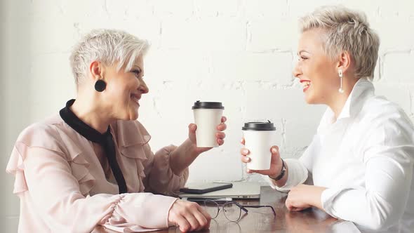 Two Female Senior Collegues Sitting Next To Each Other in an Cafe