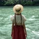 Young vintage woman in dress and straw boater hat stand near rippling mountain river, back view - VideoHive Item for Sale